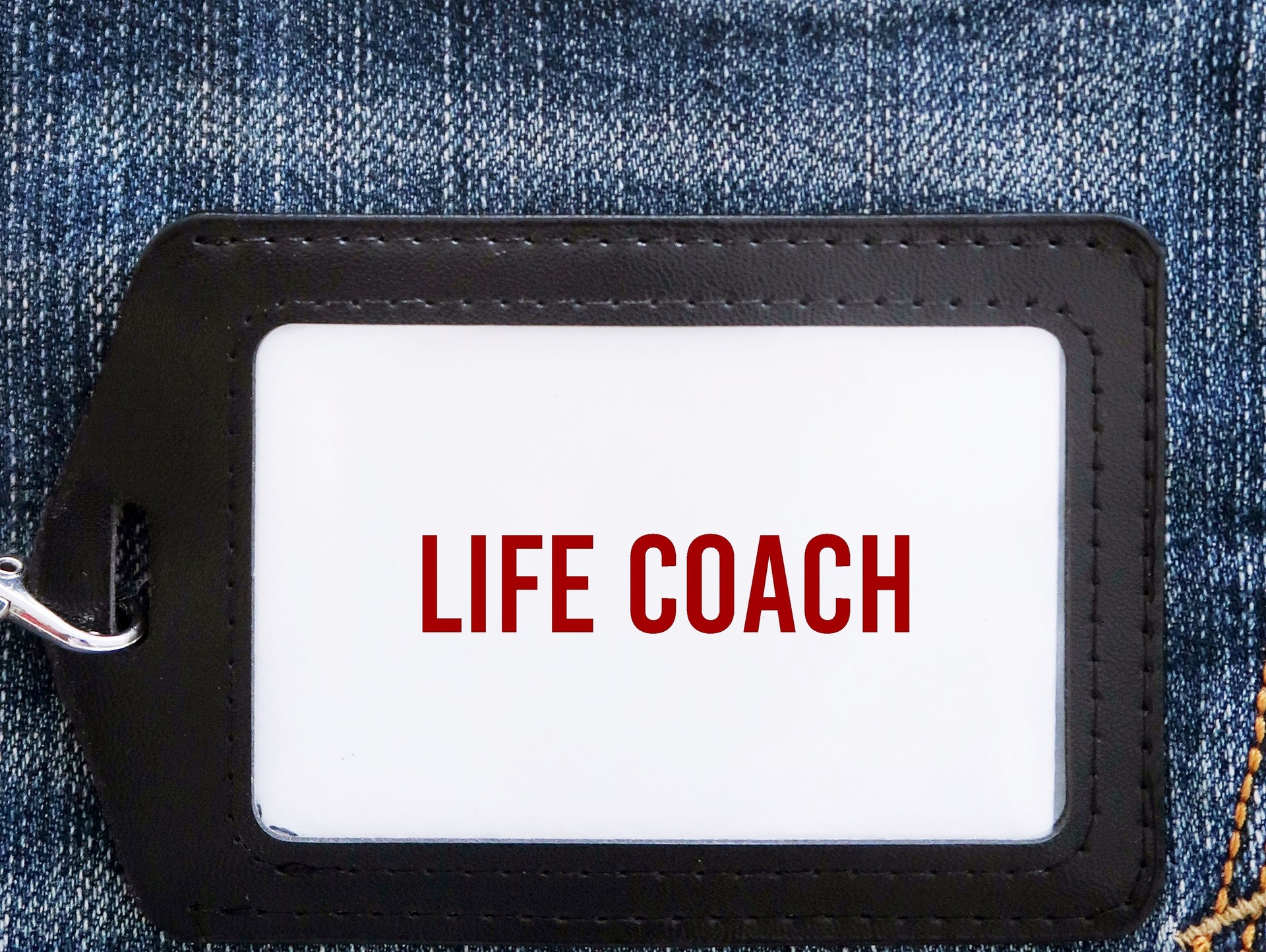 ID card in black holder with text LIFE COACH, concept of a person who aid their clients to improve relationships, careers and lives to meet and exceed personal and professional goals